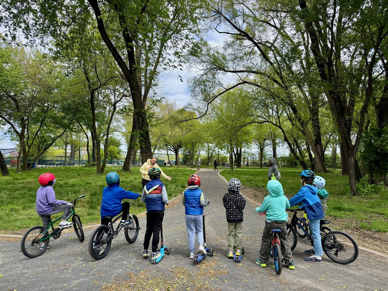 Scouts on bikes and scooters at a park path