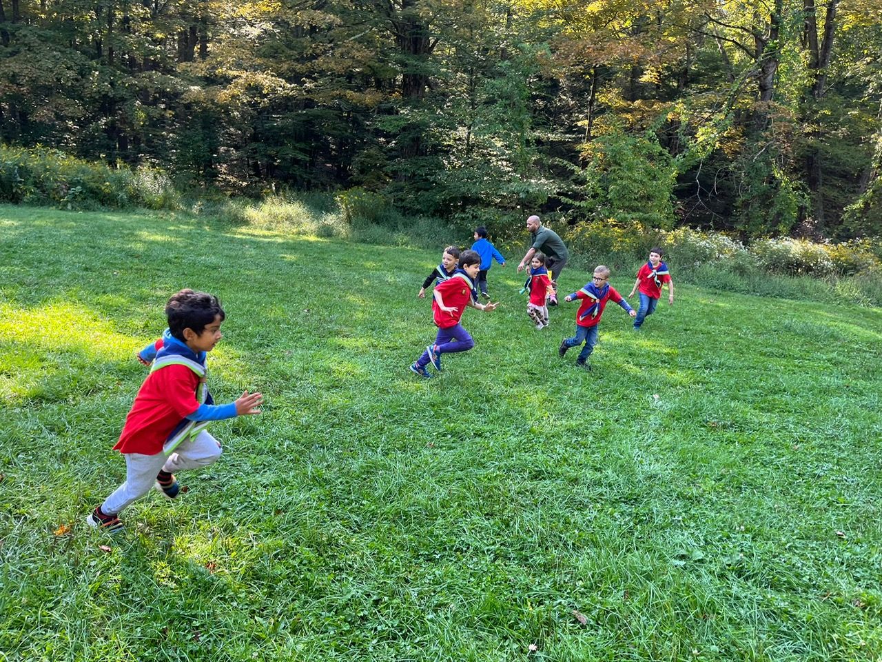 Scouts running across a field at camp