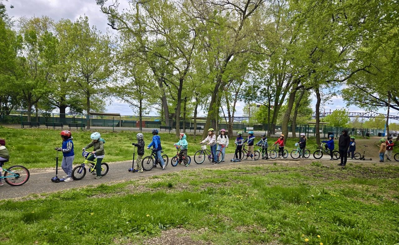 The group riding bikes and scooters along a greenway